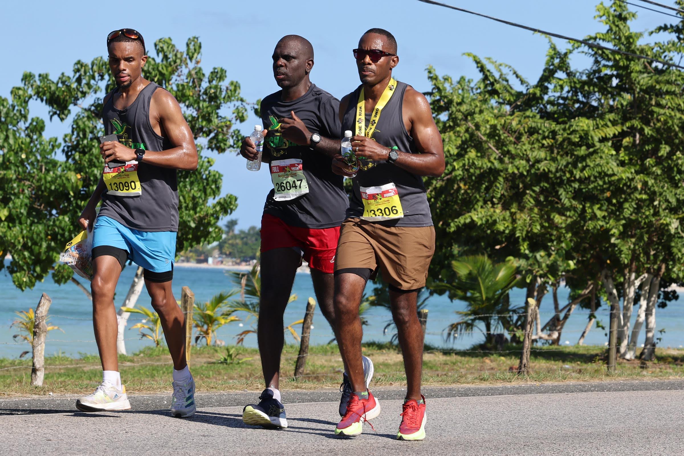 Three runners racing along a scenic coastal road